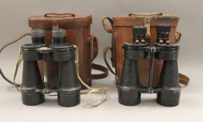 Two pairs of military binoculars, each cased. Each approximately 23 cm high.