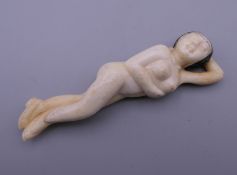 A carved bone model of a nude female. 9 cm long.