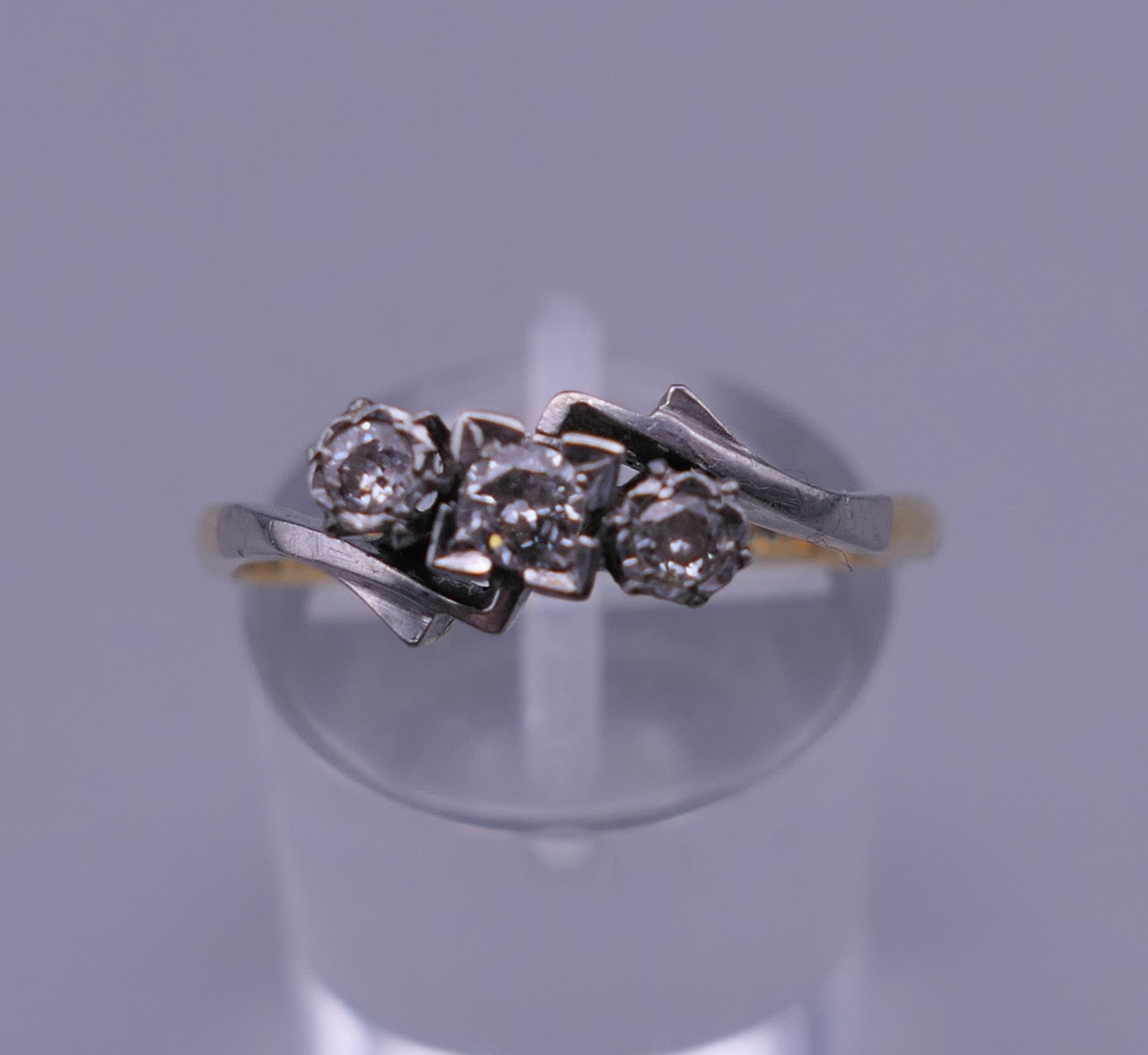 An 18 ct gold and platinum three stone diamond ring. Ring size R/S. 2.6 grammes total weight.