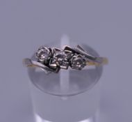 An 18 ct gold and platinum three stone diamond ring. Ring size R/S. 2.6 grammes total weight.