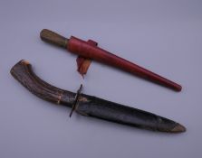 A Middle Eastern dagger with red leather sheath and a stag horn handled hunting knife.