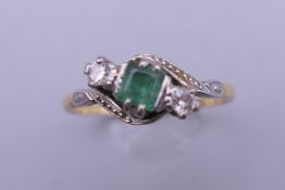 An unmarked gold diamond and emerald ring. Ring size P. 2.6 grammes total weight.