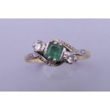 An unmarked gold diamond and emerald ring. Ring size P. 2.6 grammes total weight.