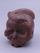 A carved wooden netsuke formed as a skull and snake. 5 cm high.