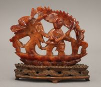 A 19th/20th century Chinese red agate carving of a man and dragon in a boat, on a wooden stand.