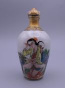A Chinese porcelain snuff bottle decorated with an erotic scene. 9 cm high.