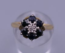 An 18 ct gold diamond and sapphire flower head ring. Ring size M. 3.4 grammes total weight.