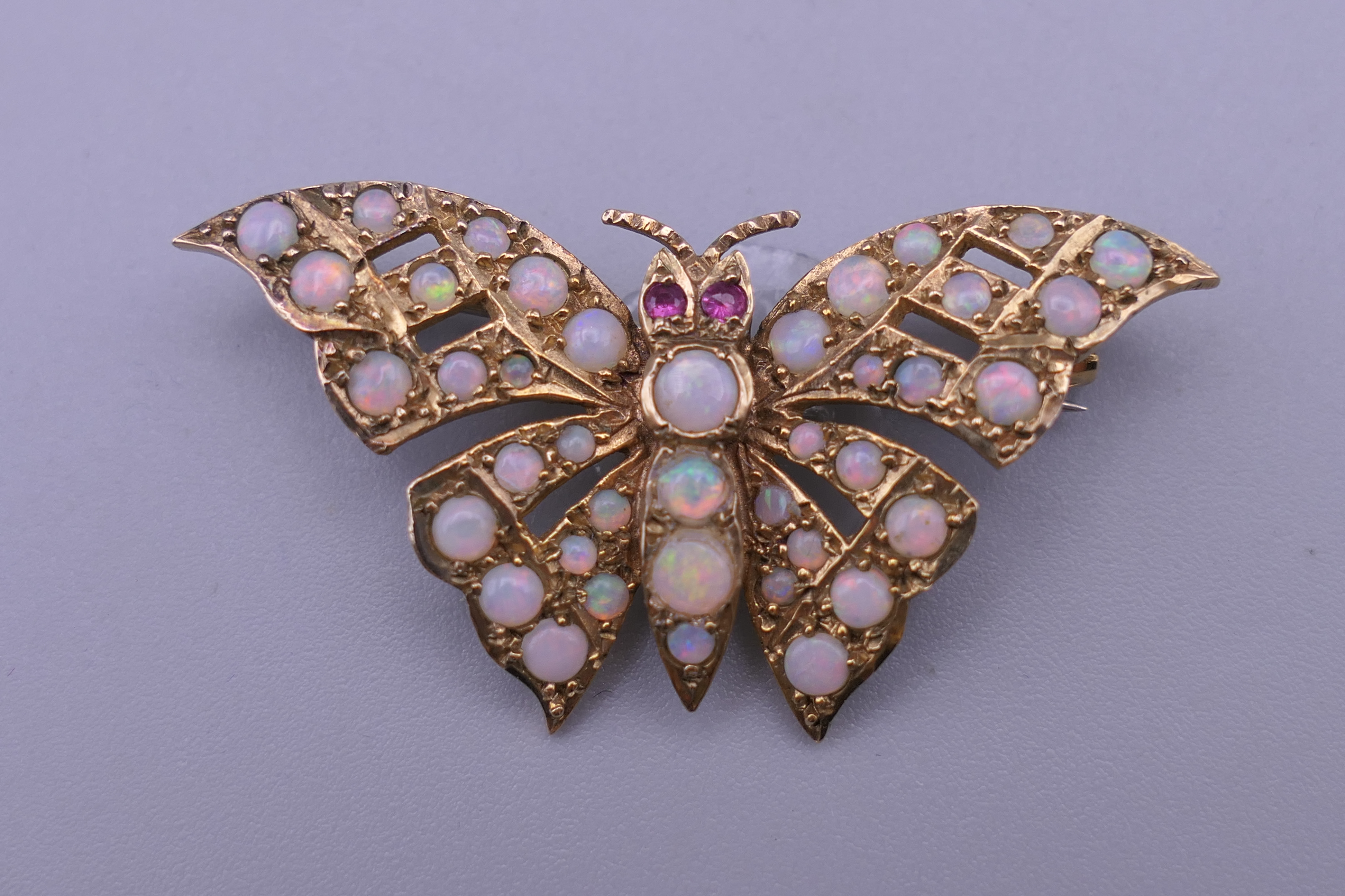 A 9 ct gold opal and ruby set butterfly brooch. 4 cm wide. 6 grammes total weight. - Image 2 of 10