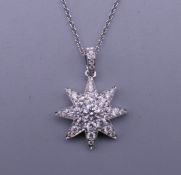 An 18 ct white gold diamond encrusted star pendant and chain. The pendant 1.5 cm wide. 3.