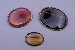 Two Art Deco agate brooches and a piece of tigers eye. The largest 7 cm wide.