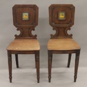 A pair of early 19th century mahogany hall chairs, each back is painted with a recumbent lion.