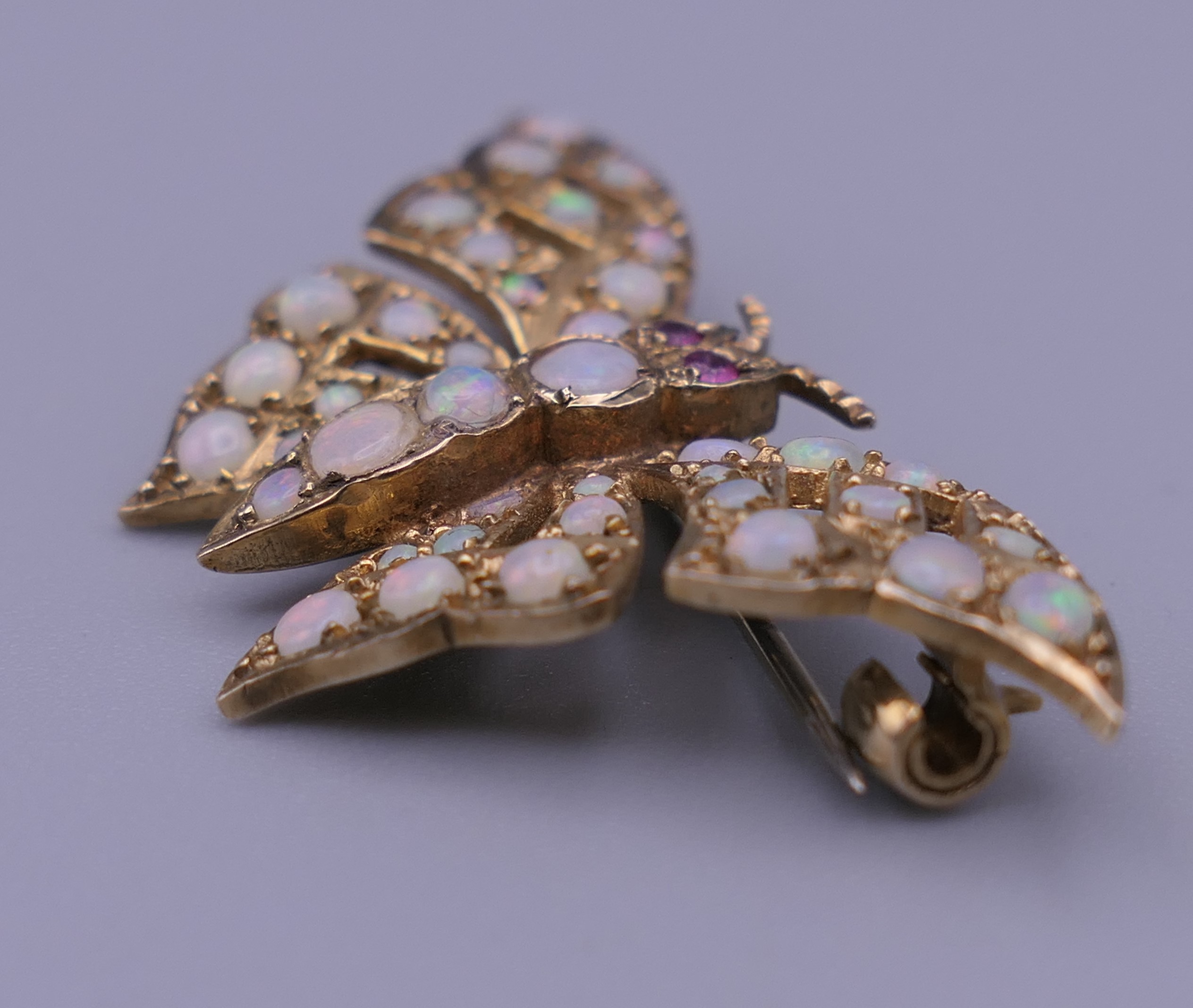 A 9 ct gold opal and ruby set butterfly brooch. 4 cm wide. 6 grammes total weight. - Image 9 of 10