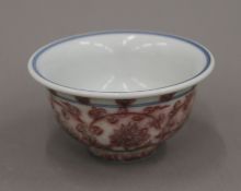 A Chinese red porcelain tea bowl decorated with calligraphy. 9.5 cm diameter.