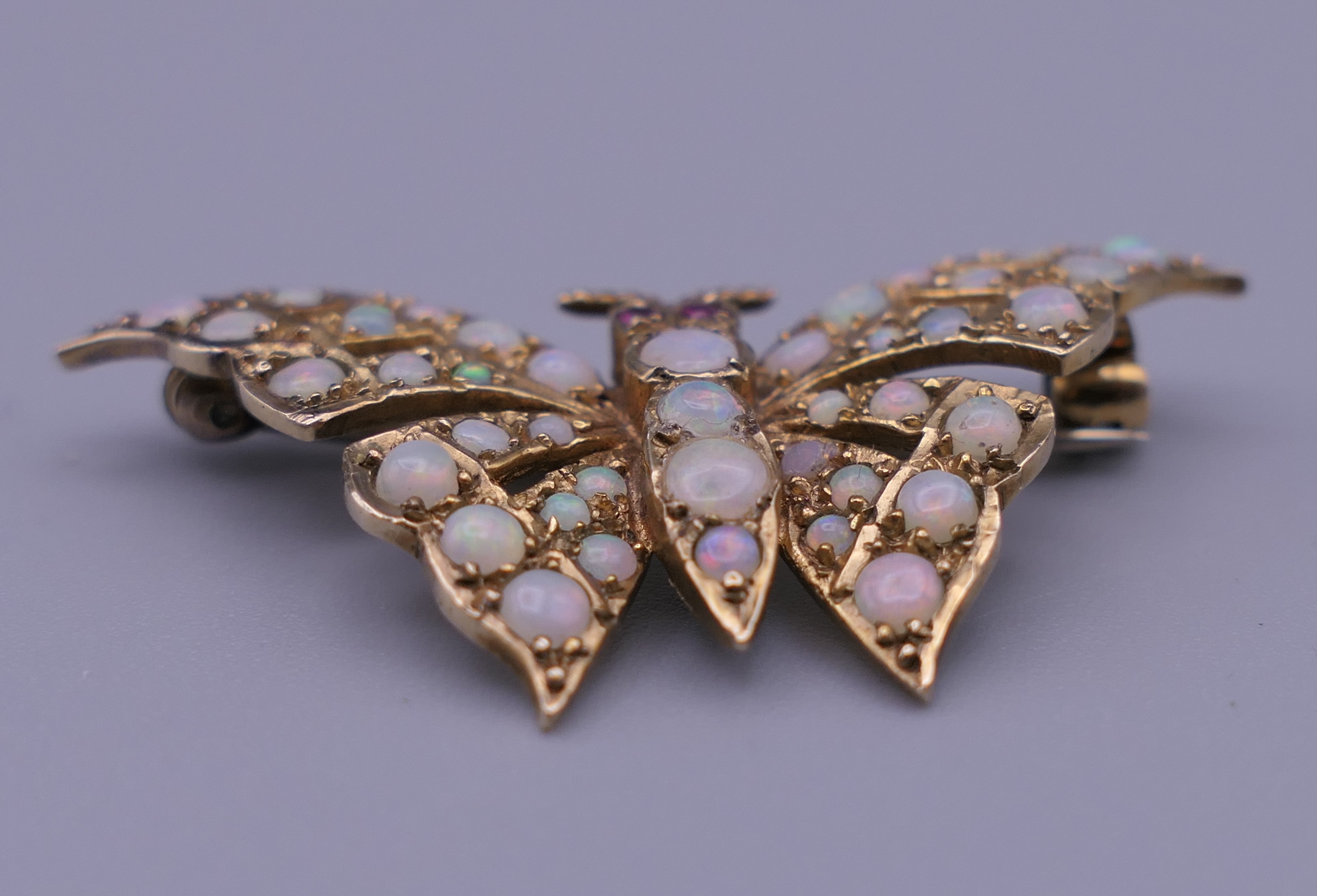 A 9 ct gold opal and ruby set butterfly brooch. 4 cm wide. 6 grammes total weight. - Image 10 of 10