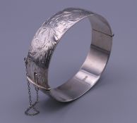 A solid silver engraved bangle form bracelet. 57.3 grammes.