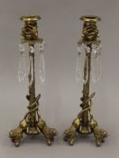 A pair of bronze candlesticks with lion form feet and glass lustre drops. Each 31.5 cm high.