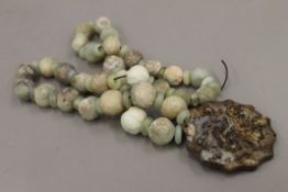 A string of carved jade beads and a pendant. The beads approximately 82 cm long.