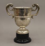 A silver twin handled trophy cup on a plinth base. 25 cm high overall. 14.