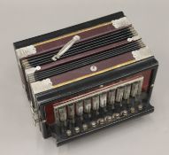 A Sterling melodeon, housed in a box. 25.5 cm wide.