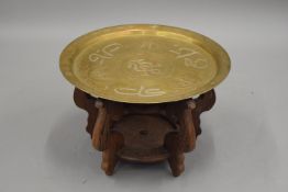 A Cairoware brass charger on a Chinese wooden stand. 48.5 cm diameter.