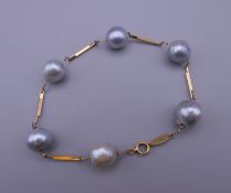 An 18 K gold and black pearl bracelet. Approximately 18 cm long.