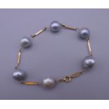 An 18 K gold and black pearl bracelet. Approximately 18 cm long.