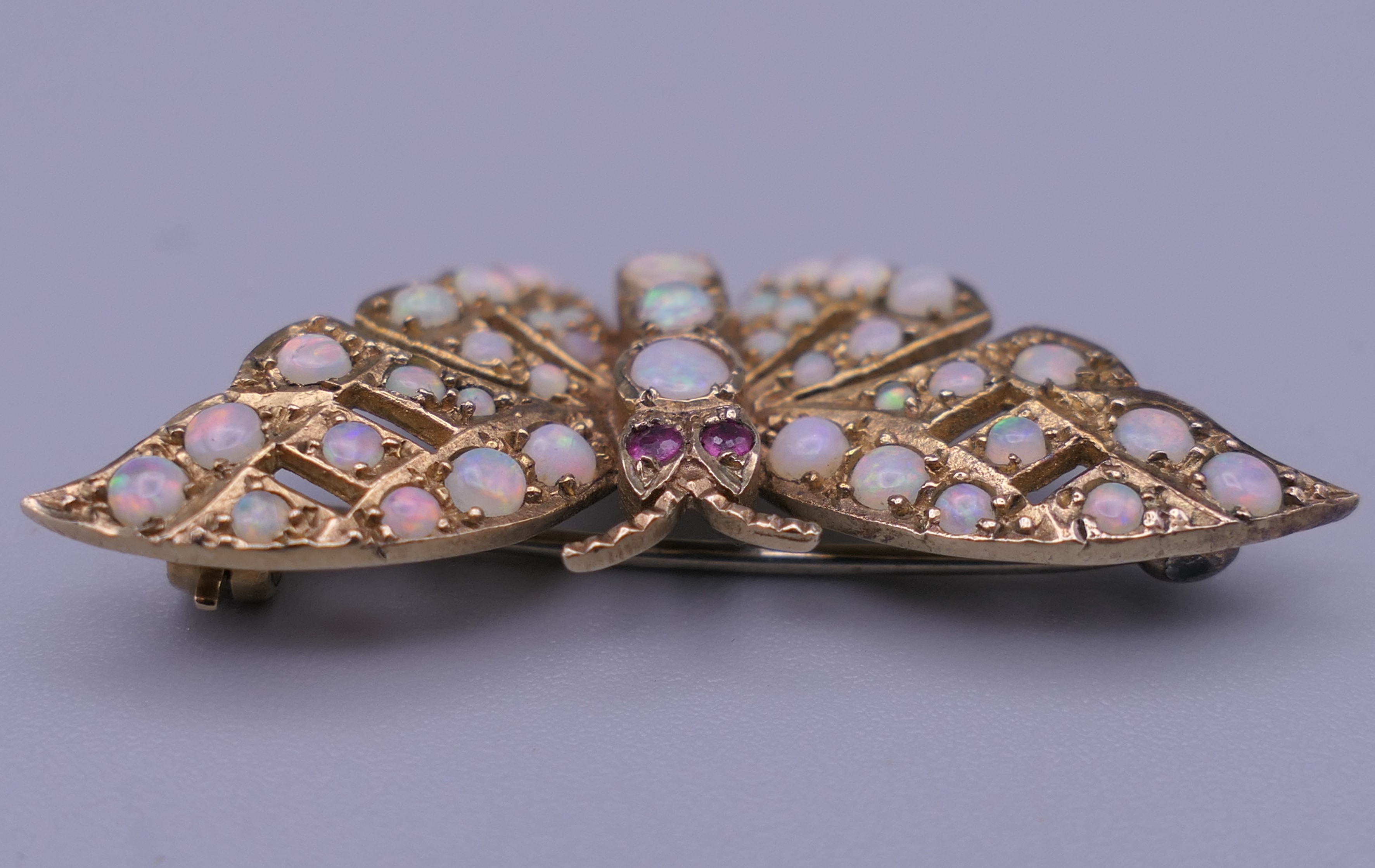 A 9 ct gold opal and ruby set butterfly brooch. 4 cm wide. 6 grammes total weight. - Image 8 of 10