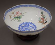 A Mandarin eggshell bowl decorated with pheasants on a hardwood stand. 19 cm diameter.