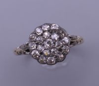 An 18 ct gold and diamond flowerhead ring. Ring size Q. 3.4 grammes total weight.