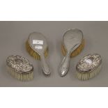 Four silver backed brushes.