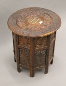 A carved Indian Kashmir folding hardwood table. 53 cm diameter.