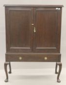 An Edwardian oak two door cupboard on stand. 96 cm wide.