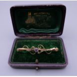 A gold amethyst and seed pearl set bar brooch. 4.5 cm wide. 1.4 grammes total weight.