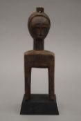 A carved wooden tribal pully mounted on a later plinth base. 24 cm high overall.