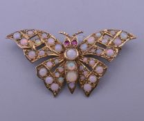 A 9 ct gold opal and ruby set butterfly brooch. 4 cm wide. 6 grammes total weight.