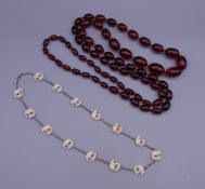 A long string of cherry amber beads and an early 20th century unmarked silver necklace set with