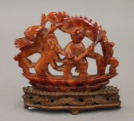 A 19th/20th century Chinese red agate carving of a man and dragon in a boat, on a wooden stand.