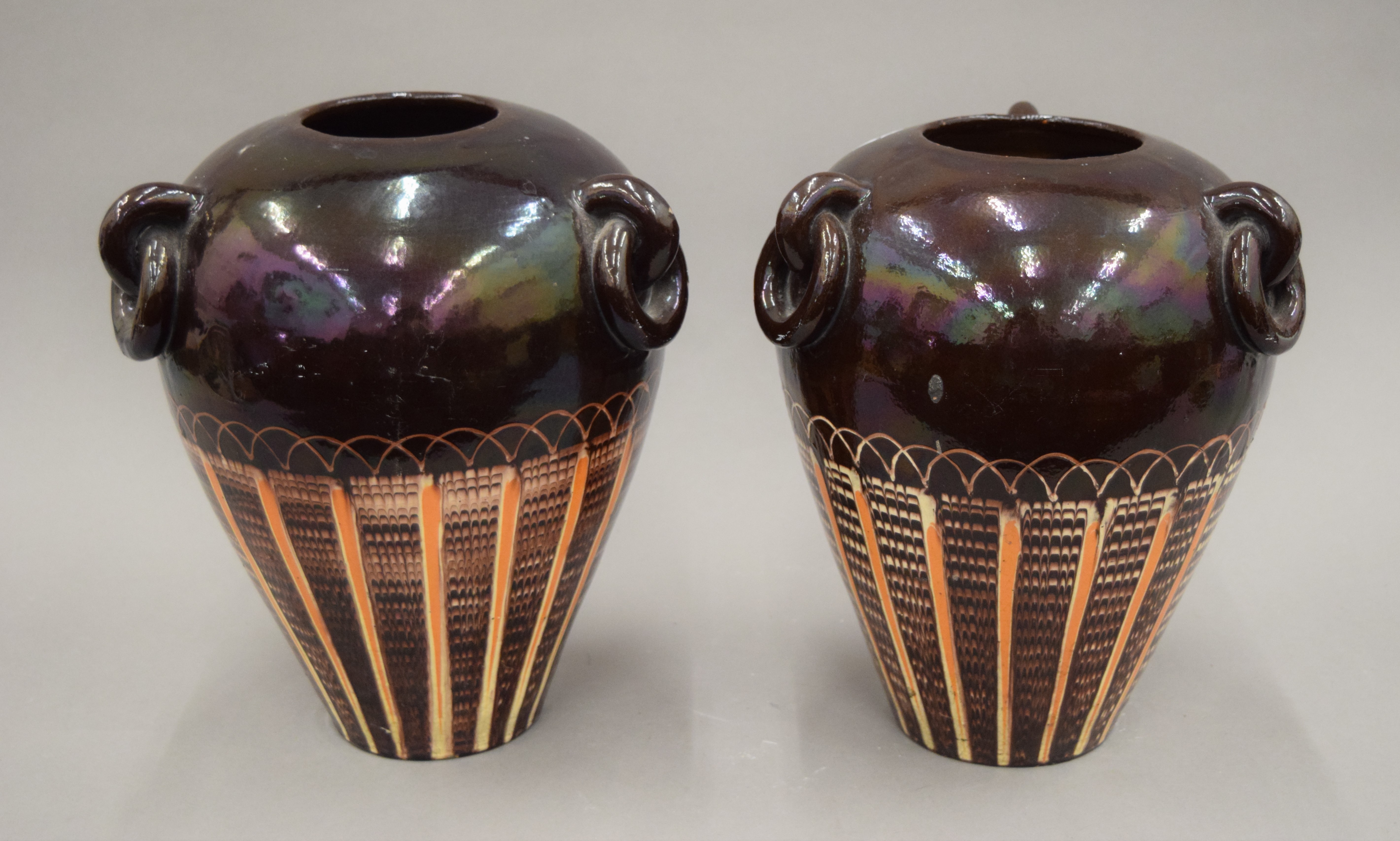 A pair of brown, cream and orange glazed vases, one with underside initialled with T.B. 26 cm high.