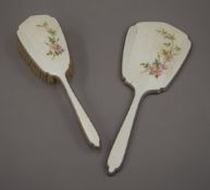 A silver and enamel dressing table brush and a mirror.