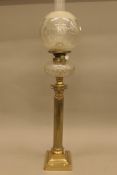 A brass Corinthian column oil lamp with cut glass reservoir and etched glass shade. 88 cm high.