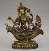 A Tibetan gilt bronze four armed deity inset with coral and turquoise. 26 cm high.