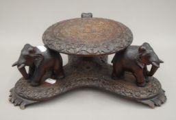 An Eastern carved wooden stand formed with elephants. 13.5 cm high.