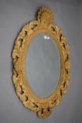 A carved wooden mirror with bevelled glass. 112 cm high.