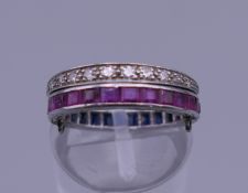 An unmarked white gold diamond, ruby and sapphire ring. Ring size J/K.