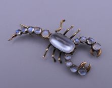 An unmarked gold moonstone set scorpion brooch. 4 cm wide.