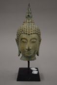 A patinated bronze Thai Buddhas head on a display stand. 23 cm high.