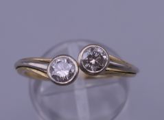 An 18 ct gold two stone diamond ring. Ring size M/N. 3.9 grammes total weight.