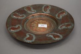 A 19th century repousse decorated copper dish. 29 cm diameter.