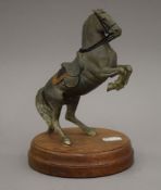 A patinated model of a rearing horse mounted on a wooden plinth base. 19.5 cm high.