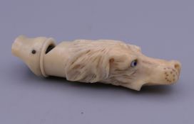 A 19th century whistle carved as a dog's head with glass eyes. 6 cm long.